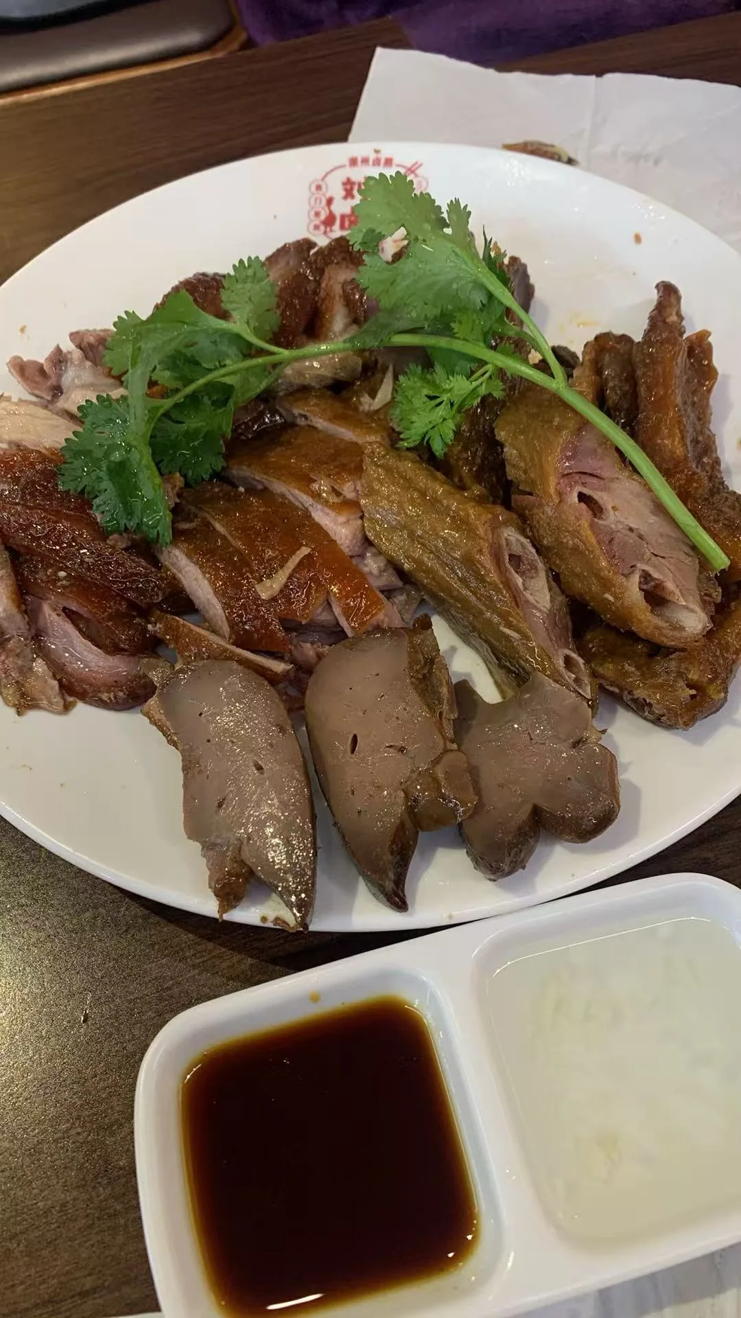 In Chaozhou: A platter of chopped braised poultry and sliced offal, garnished with coriander, with two dipping sauces / 在潮州拍摄：切块的卤禽肉与切片内脏拼盘，上覆香菜，盘前放着两种蘸料