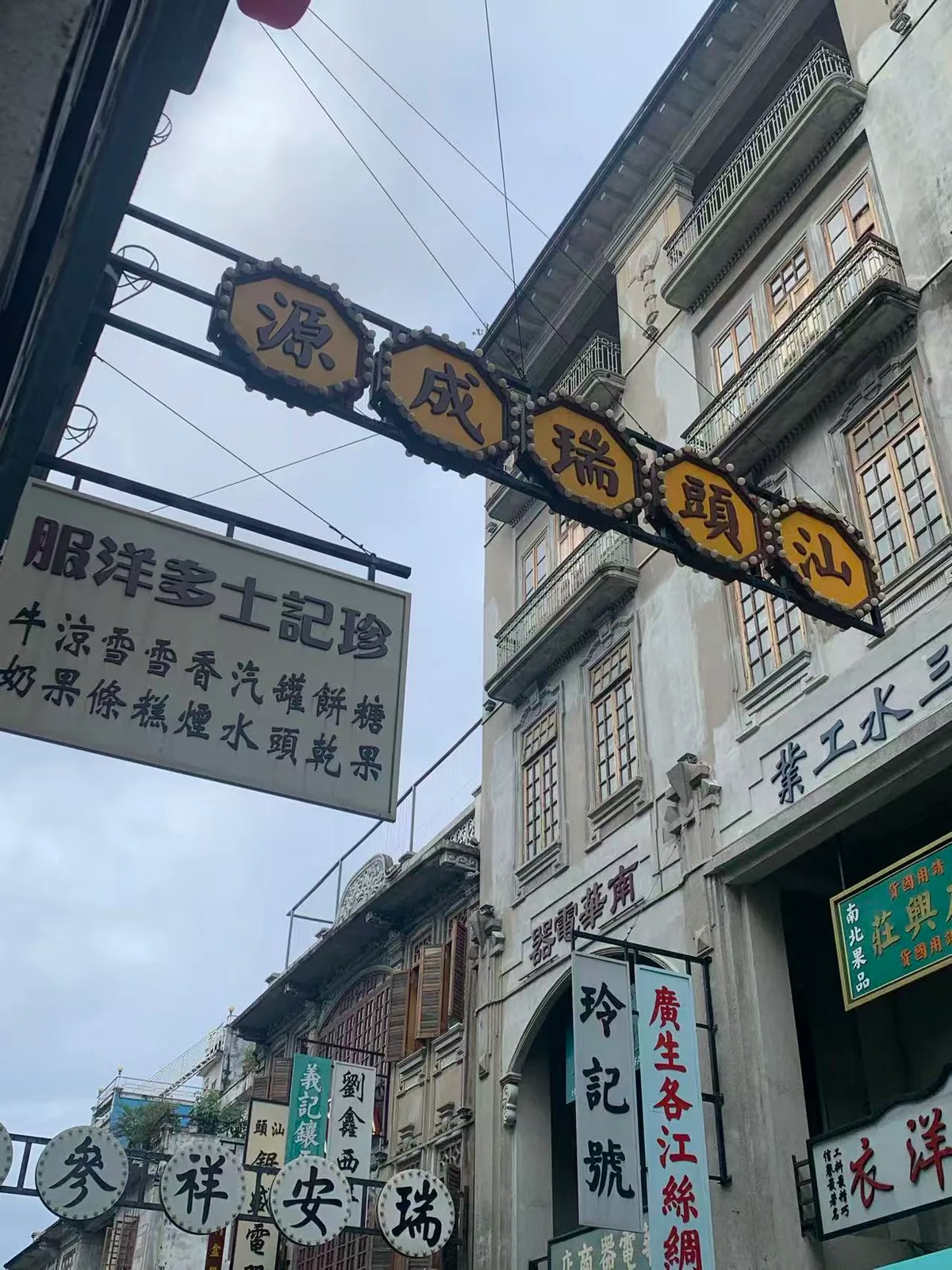Old shop signs suspended over a street lined with arcaded buildings and wooden windows / 骑楼街道上悬挂着老式商号招牌，楼上排列着木窗